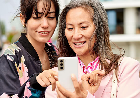 Zwei Frauen nutzen gemeinsam ein Smartphone, digitale Teilhabe und generationenübergreifendes Lernen