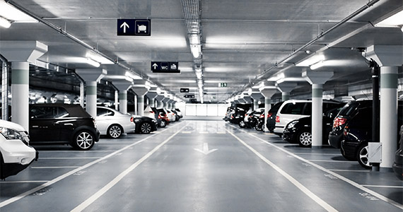 Tiefgarage mit Fahrzeugen beidseitig, klare Fahrbahnmarkierungen und Hinweisschilder
