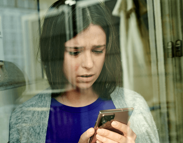 Eine junge Frau schaut besorgt auf ihr Smartphone. Eine junge Frau schaut besorgt auf ihr Smartphone.