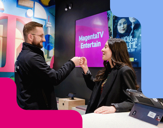 Lobby16 Zwei Personen begrüßen sich mit einer Faust-Geste in einem modernen Telekom-Shop, im Hintergrund Werbung für MagentaTV.