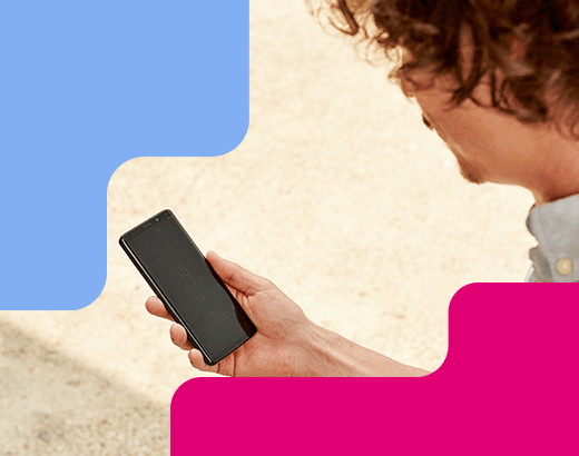 Plaudernetz Mann mit lockigem Haar hält draußen ein Smartphone in der Hand und blickt konzentriert auf den Bildschirm bei Tageslicht.