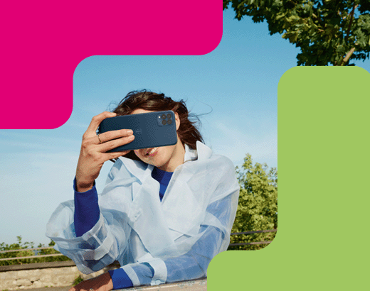 T Phone Junge Frau im transparenten Regenmantel macht draußen bei blauem Himmel ein Selfie mit ihrem Smartphone.
